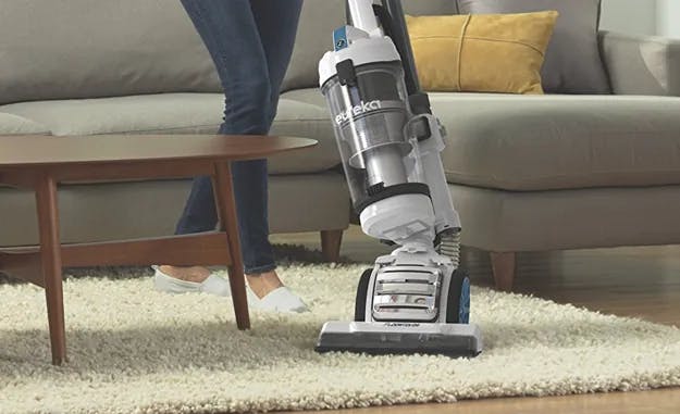 A person vacuuming a fluffy white living-room rug